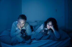 couple on phones ignoring each other in bed