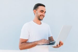 man smiling while holding his laptop