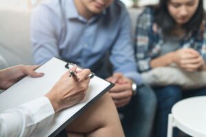 woman taking notes while couple talks in therapy