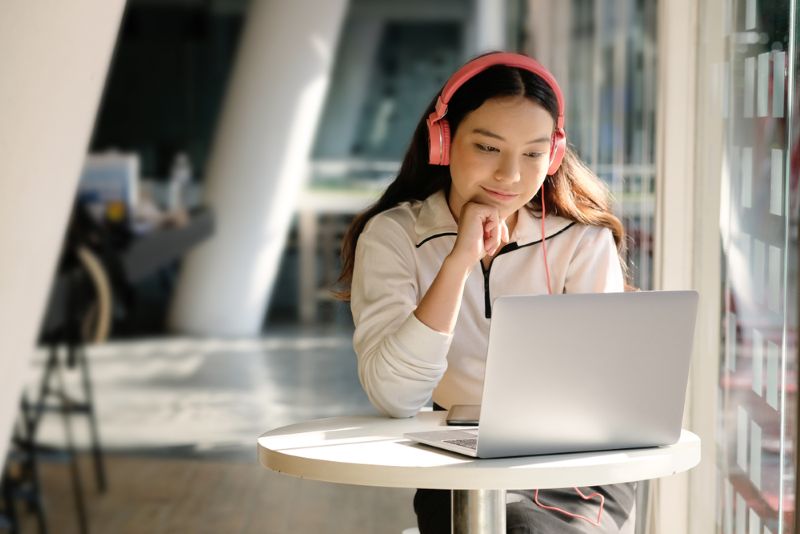 teenager with headphones on using their laptop