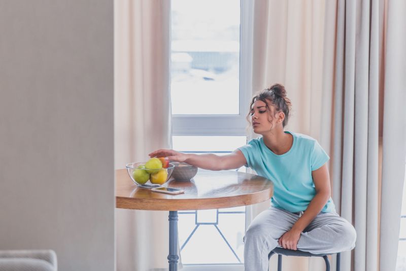 a young woman reaching for a piece of fruit early in the morning