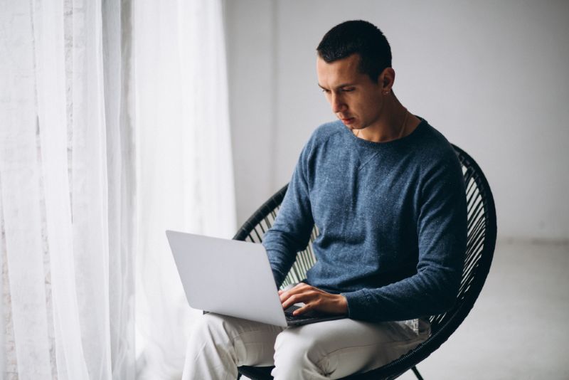 young man sitting in a chair at home on his laptop