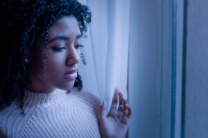 Cold image of a young woman sadly looking out the window
