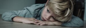 Cold portrait of a sad young boy laying on the floor