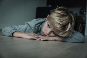 Cold portrait of a sad young boy laying on the floor