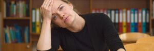 Stresesd woman sitting in a library with her hand on her head