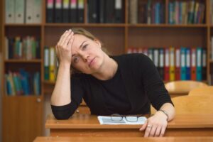 Stresesd woman sitting in a library with her hand on her head