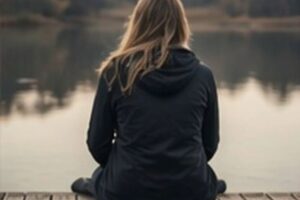 Woman sitting contemplatively on a dock staring into the distance