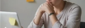 Adult woman with ADHD focused at her laptop surrounded by sticky note reminders