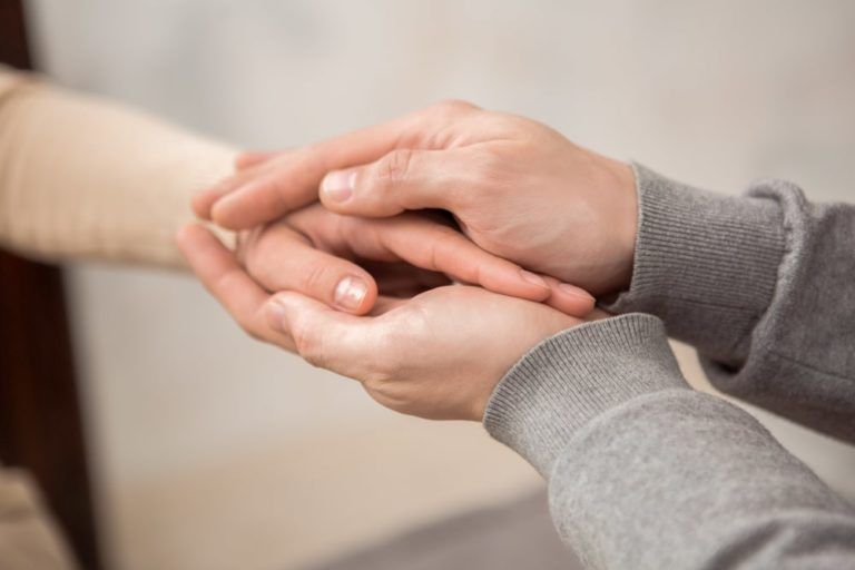 A female hand being held in between to male hands offering support