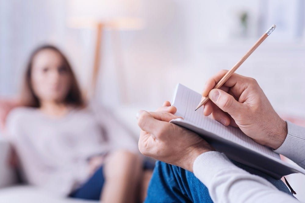 Therapist taking notes while client talks