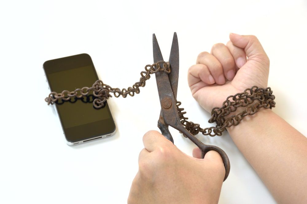 Using scissors to cut a metal chain linking a cell phone to a wrist