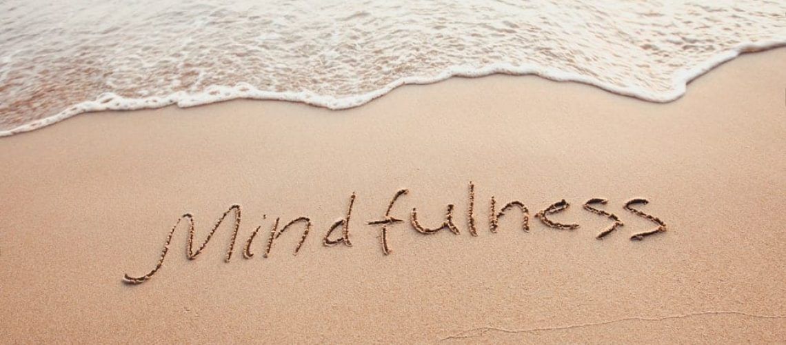 The word "mindfulness" written in the sand at the beach