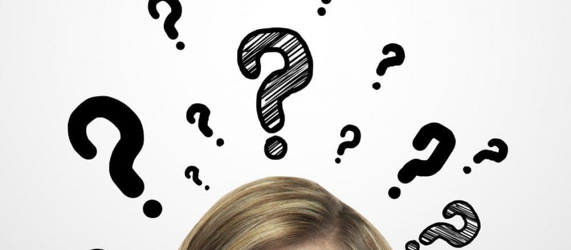 Upper half of woman's face surrounded by question marks